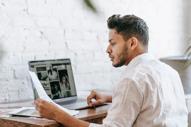 An accountant reading a supplier invoice at his laptop