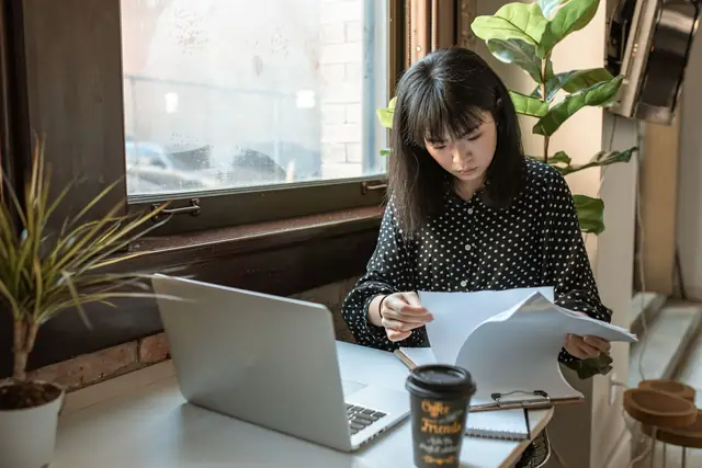 A founder reading her incorporation papers at a window table