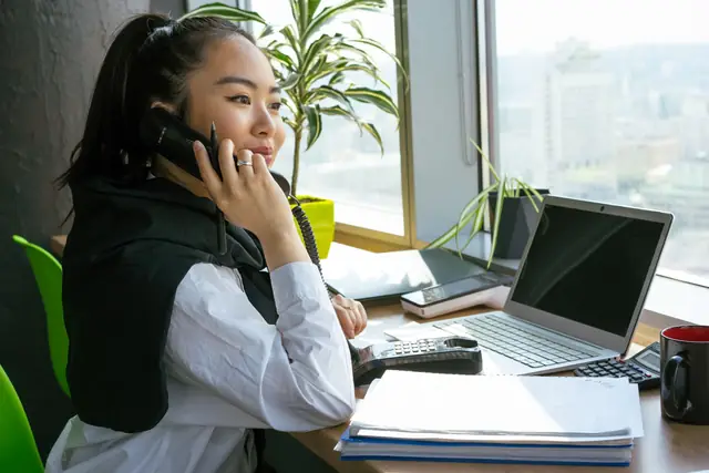 Our payroll lead on the phone with a client at her desk by the window