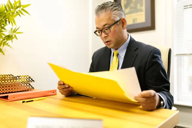 A senior accountant reading a tax file in a yellow folder