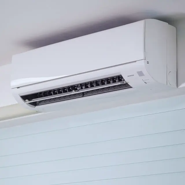 A white inverter wall unit mounted level just below the ceiling, with no visible pipes