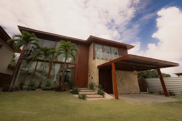 Detached house with deep timber eaves, a stone-clad base, tall glazing and palm trees in the front garden