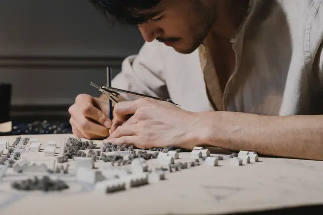 Close-up of hands placing small blocks on an urban site model