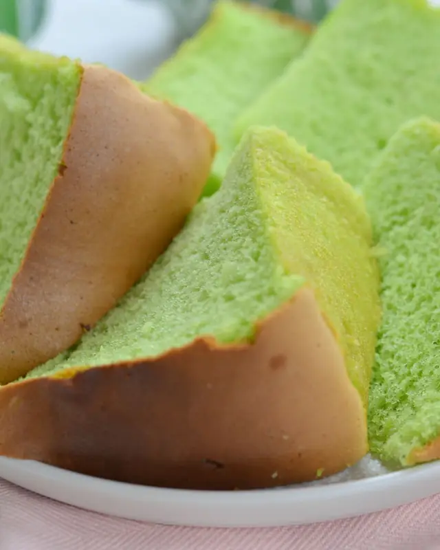 Slices of bright green pandan chiffon cake on a white plate
