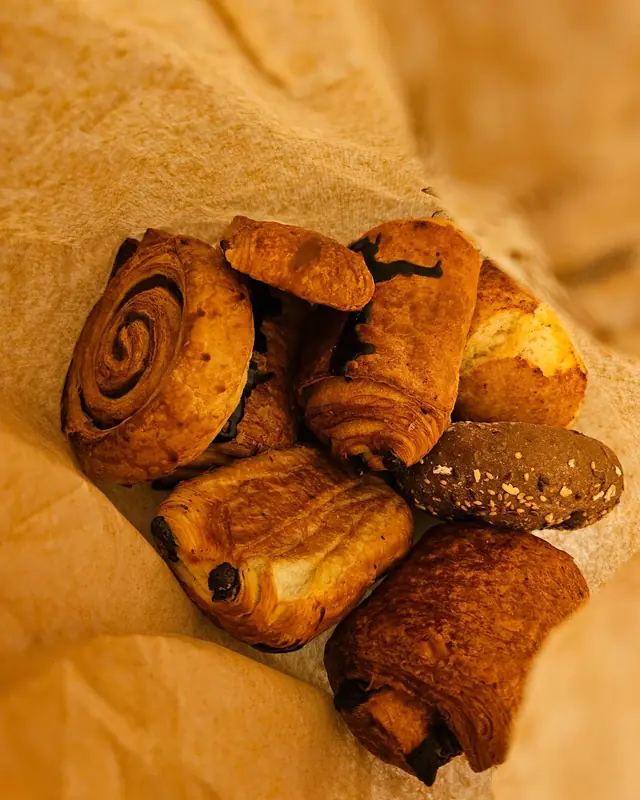 Assorted croissants, pain au chocolat and swirl pastries in a paper bag