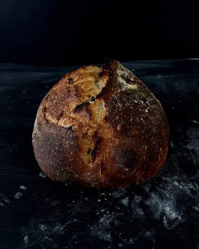 A dark-crusted country sourdough loaf with a scored, crackled top