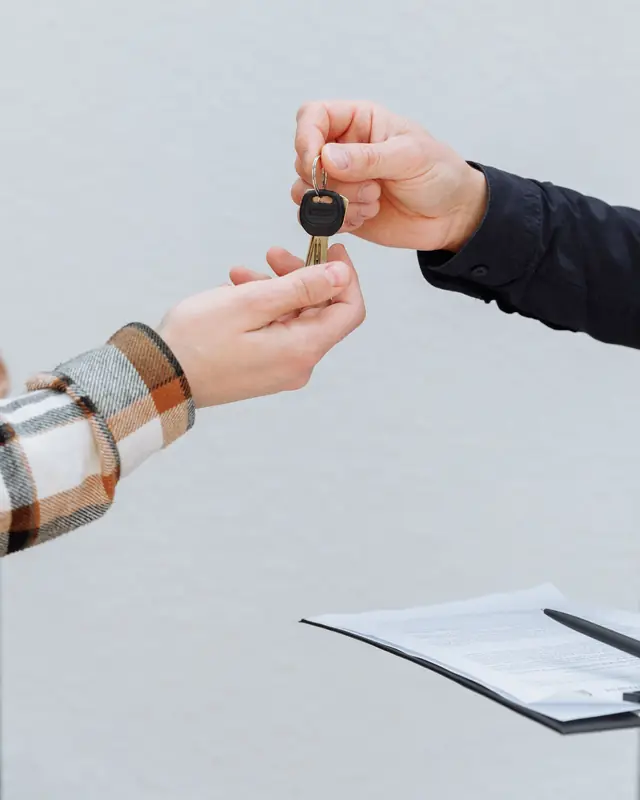 A car key handed from one person to another over the signed papers