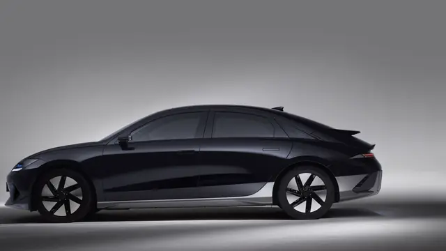 Black electric fastback saloon side-on in a grey studio