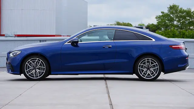 Deep blue grand tourer coupé side-on on a rooftop car park