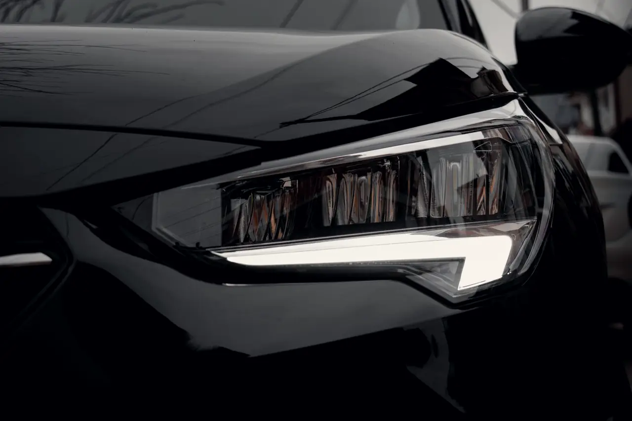 After: the same black paint corrected, deep and clear, with crisp reflections around the headlight