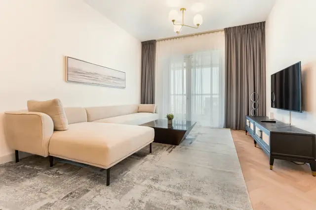 Clementi living room with a pale modular sofa, sheer and charcoal curtains, a low black console and a herringbone floor