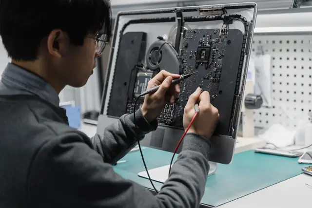 Ryan, a Keelgrid engineer, repairing a computer at the workbench in the Ubi office