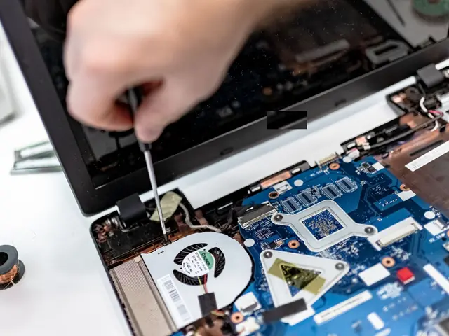 An open laptop on the Keelgrid bench, its battery being removed with a small screwdriver
