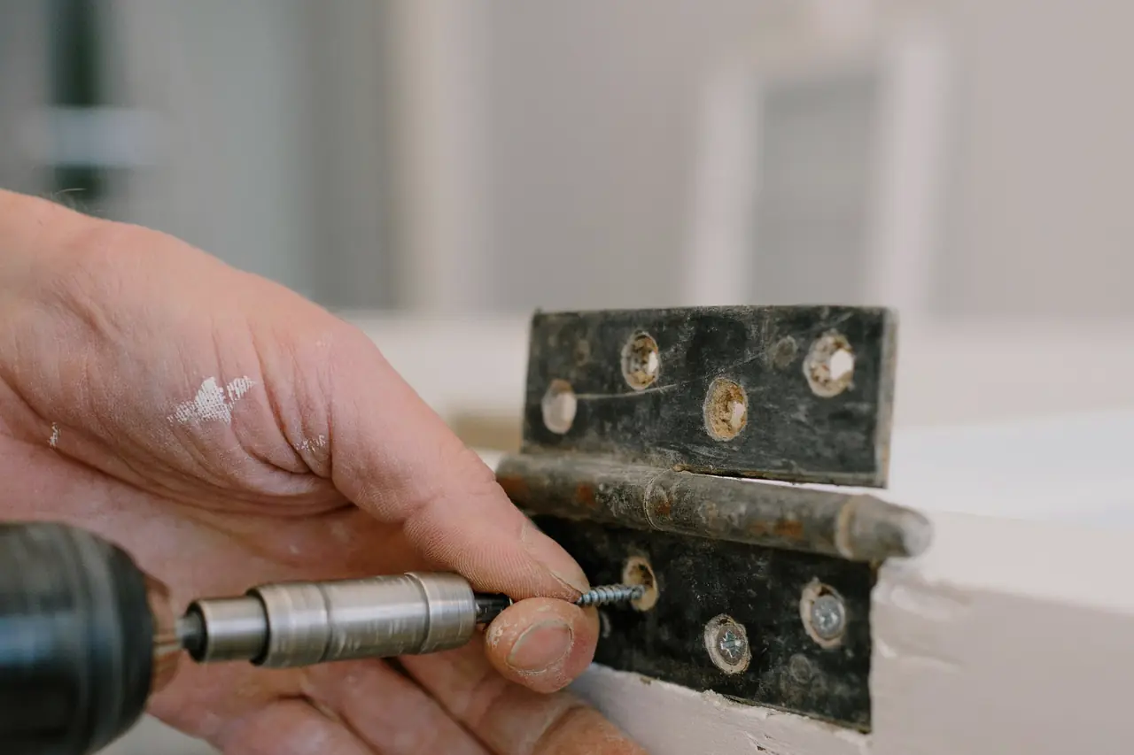 Installer driving screws into a hinge with a cordless drill