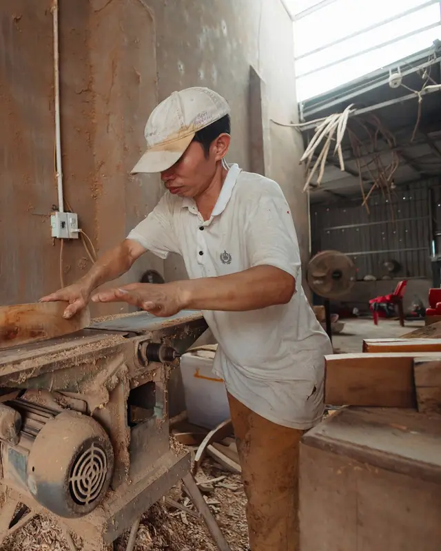 Kok Seng feeding a timber board across a jointer in the workshop