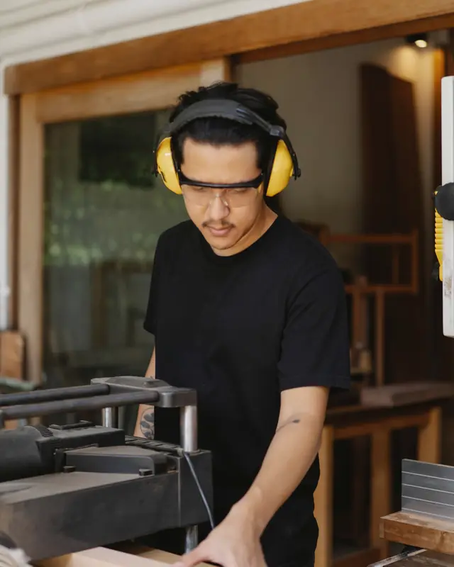 Marcus in safety glasses and ear defenders at a machine in the workshop