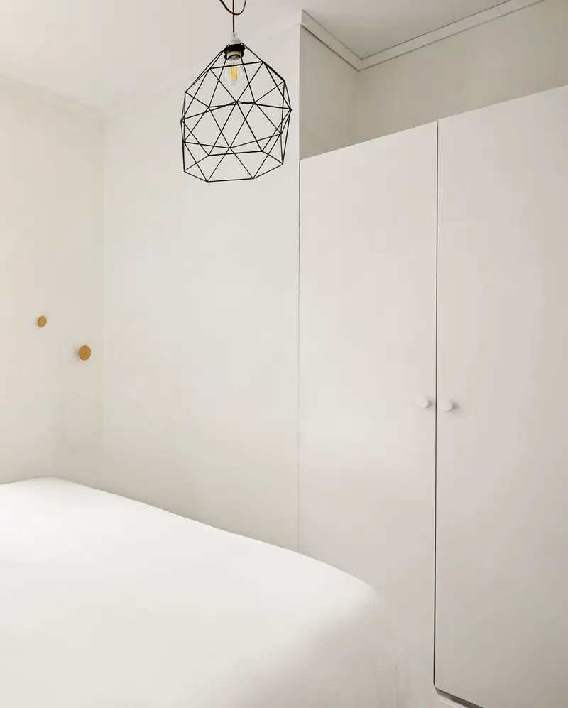 White bedroom with a full-height built-in wardrobe and a black wire pendant lamp