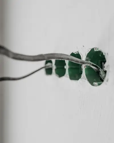 Electrical wires coming out of a fresh socket box in a white wall