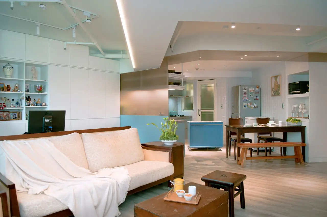 Living room with a white sofa, wall-to-wall shelving and a pale blue kitchen island behind