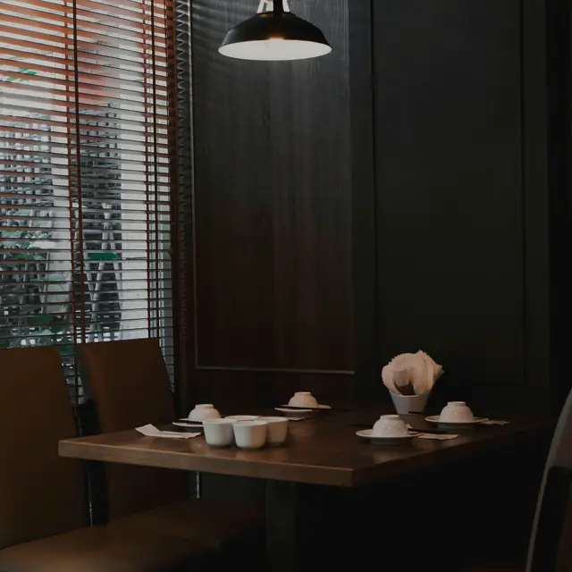 A quiet table set with teacups under a single black pendant lamp