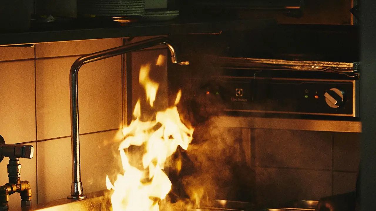 A wok bursting into flame on a restaurant burner during service