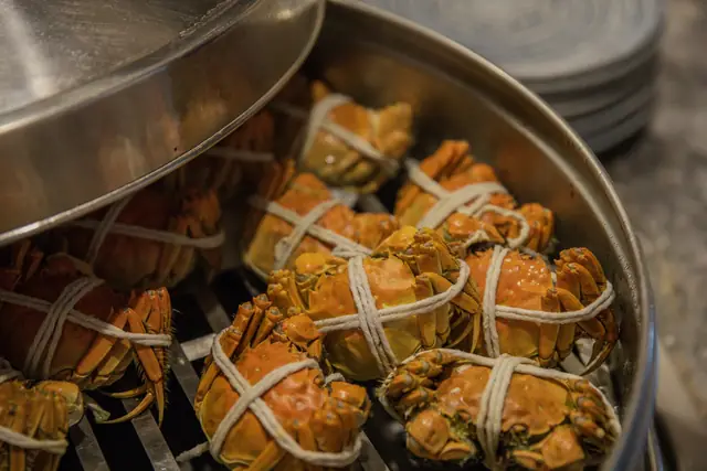 Shanghai hairy crabs tied with string, sitting in a steamer