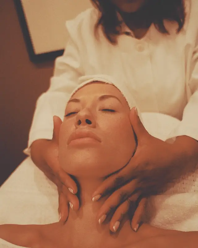 The therapist's hands cradling a guest's jaw and neck during the massage.