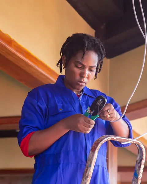 An electrician on a ladder holding a length of cable