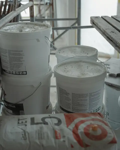 White paint pails stacked on a building site floor