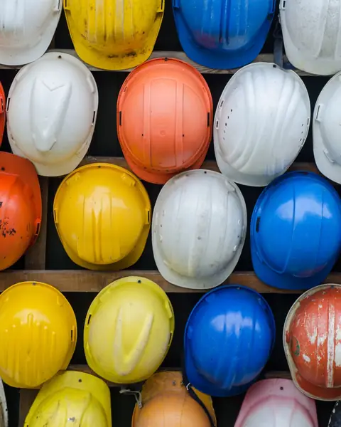 Safety helmets in white, yellow, orange and blue racked on a wall