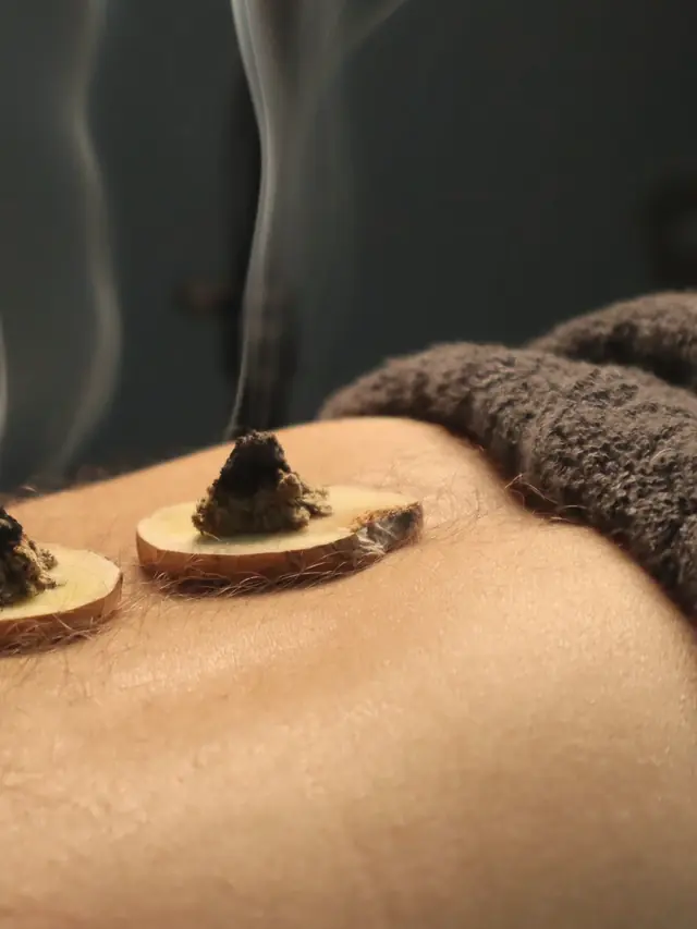 Small cones of mugwort smouldering on slices of ginger, with thin smoke rising