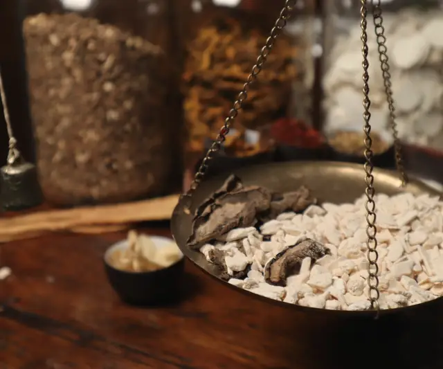 Sliced dried herbs weighed on a traditional hanging brass scale