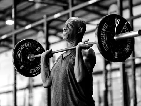 A member in his fifties holds the bar on his shoulders before a squat