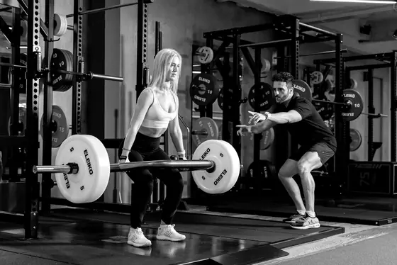 Ian coaches a member through a deadlift on the platform