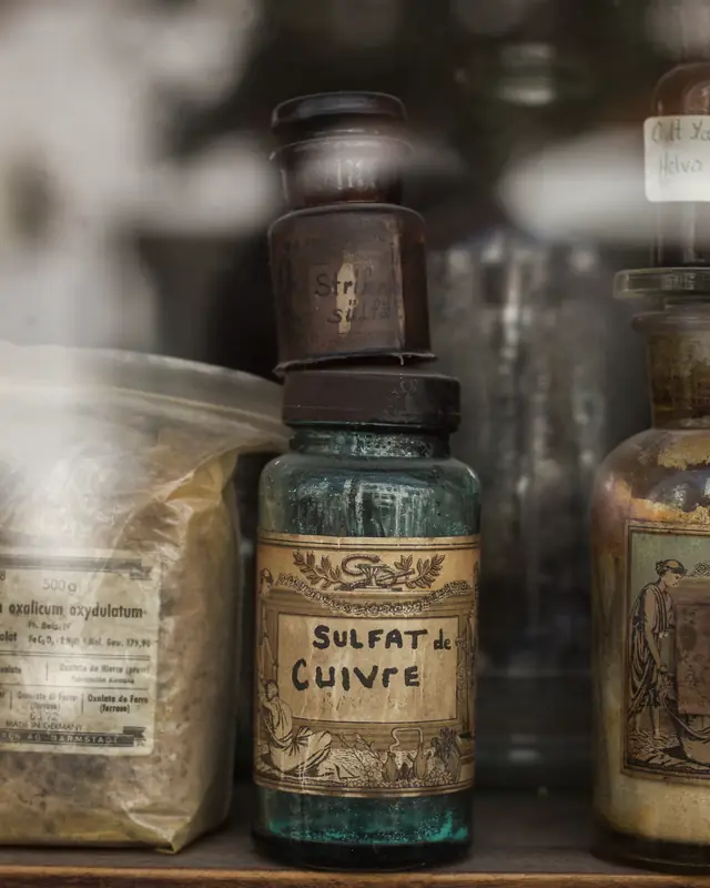 An antique apothecary bottle labelled Sulfate de Cuivre, filled with blue copper sulfate crystals