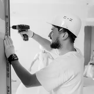 An installer in a hard hat drilling into a freshly painted wall